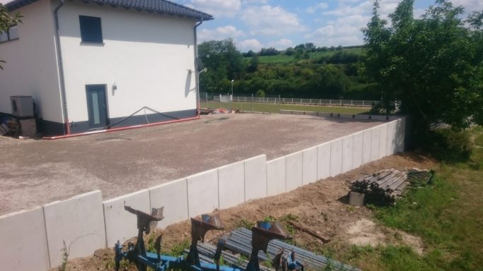 Mauer aus L-Steinen und verdichtete Fläsche